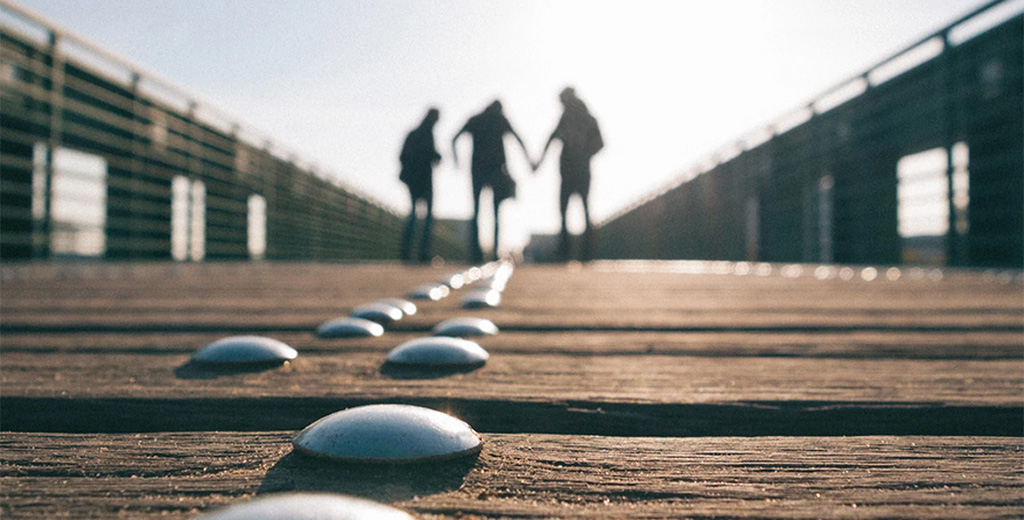 Silhouette of three people walking on boardwalk