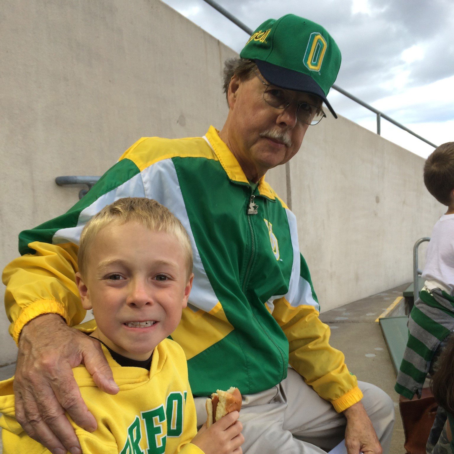 Poppy trying to warm up his grandson at a cold Ducks football game