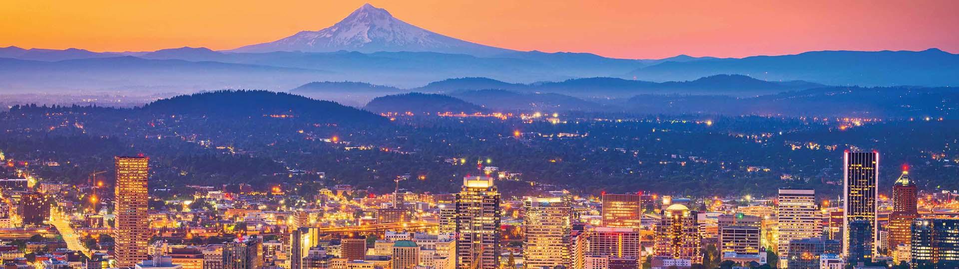 Overview of Portland lit up at night with mountains in background
