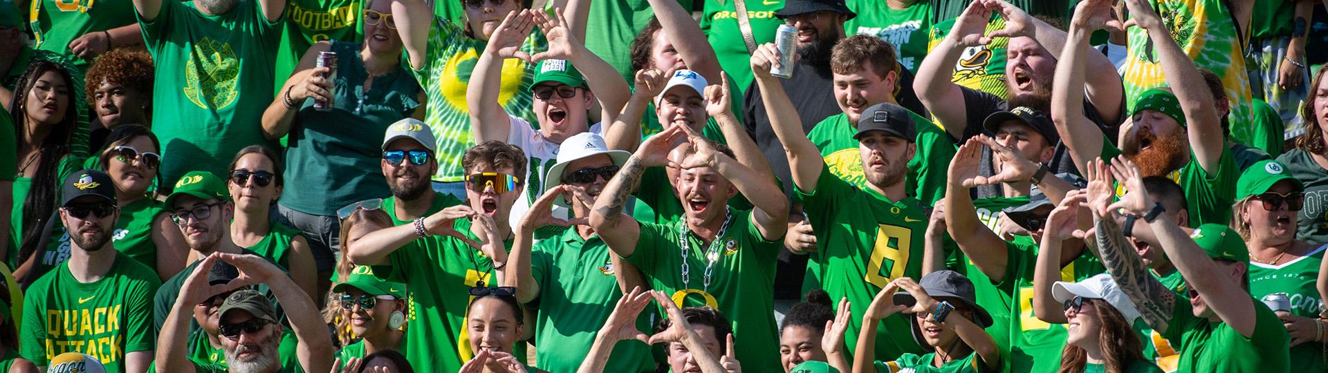 Ducks fans in green throw their "O" while attending an Oregon football game