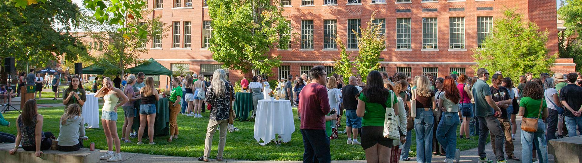 A crowd of people mill around the quad outside Chapman Hall in the background.