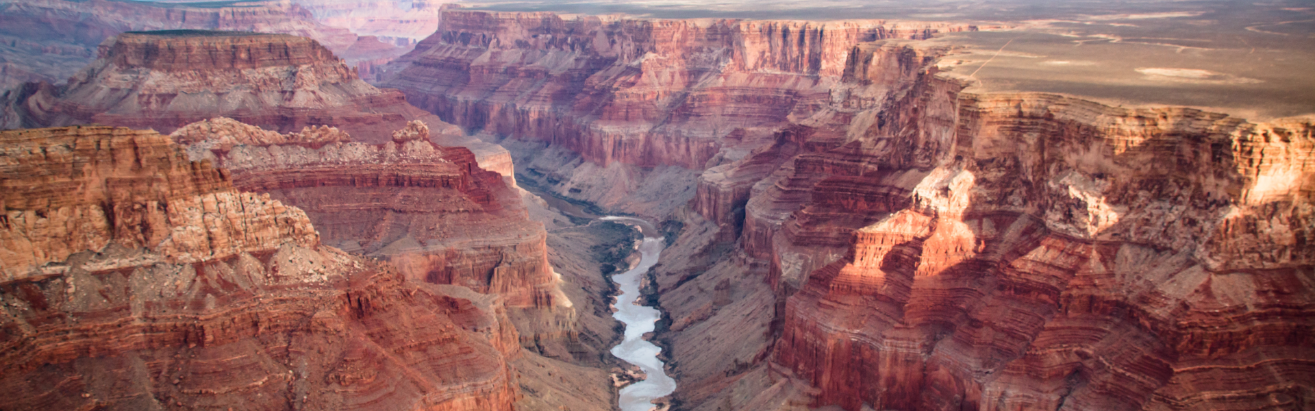 A river runs through the red striped walls of the Grand Canyon.