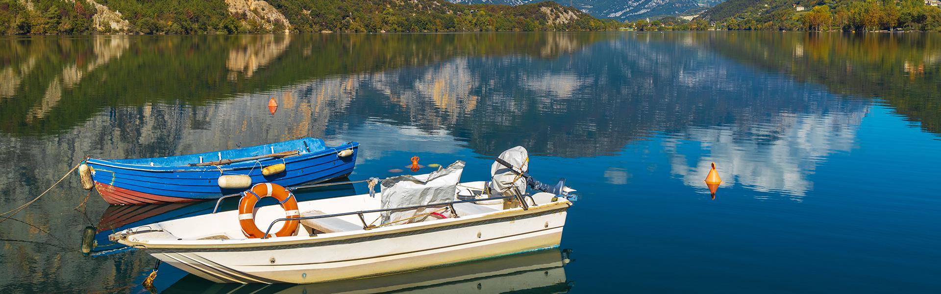 Two boats sit on the top of a blue lake reflecting the hills around it.