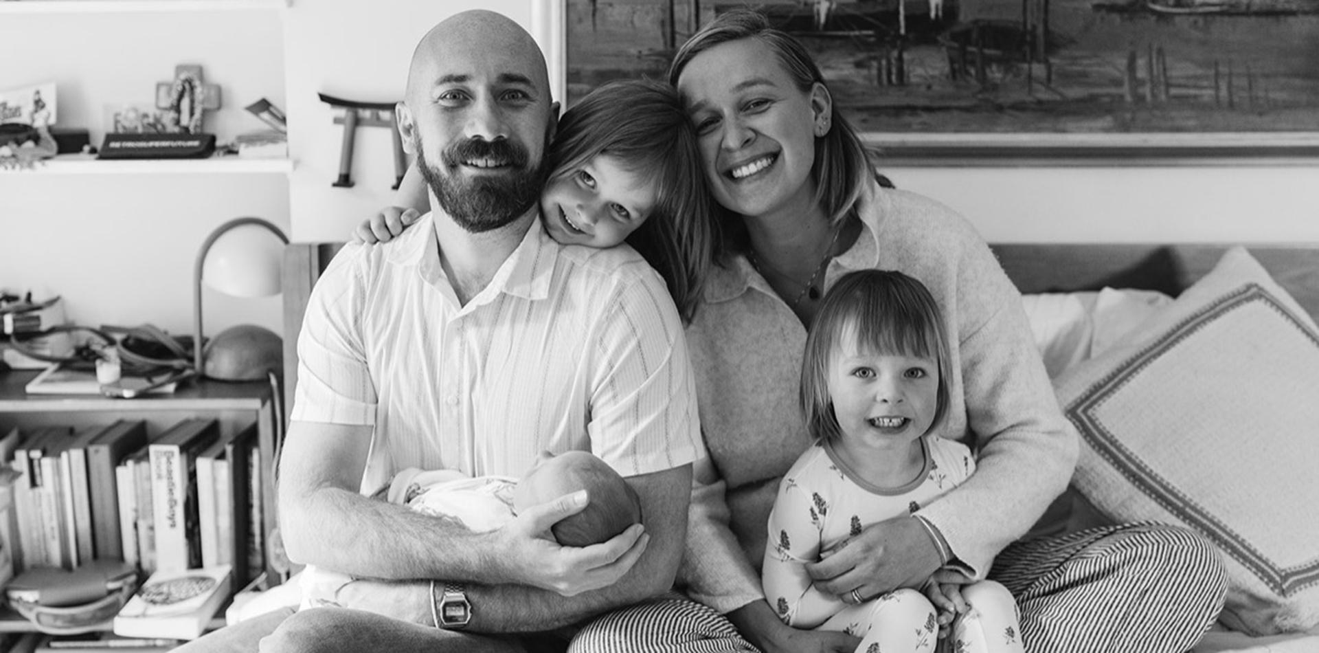 A black and white Flannery family photo of a man, and woman, two little girls, and a baby.