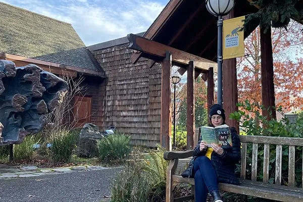 Woman reading on a bench on the UO campus