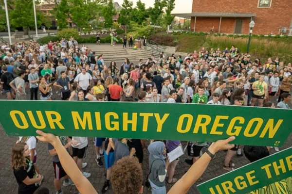 Our Mighty Oregon sign being help up by a fan