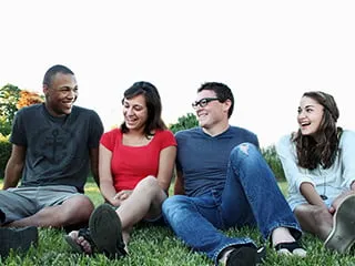 Four people sitting on grass talking