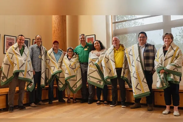 Jason Younker (center, green shirt) and UO interim President Patrick Phillips presented representatives of Oregon's nine federally recognized Native A