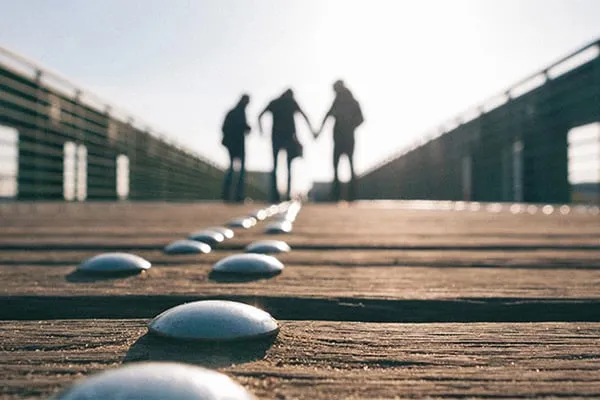 Silhouette of three people walking on boardwalk