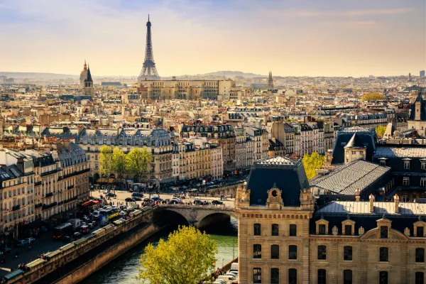 The Eiffel Tower rises above the streets of Paris, the Seine running between buildings.
