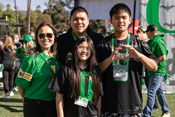 Group of people wearing green and black sports jerseys at an outdoor event.