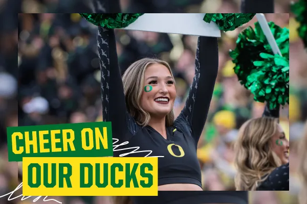 An Oregon Ducks cheerleader dressed in black raises her arms. Green and yellow text in the bottom left corner says "Cheer on our Ducks" with a white scribble behind the letters. 