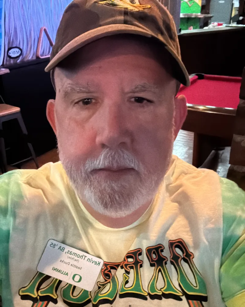 Kevin Thomas wears a green and yellow tie dye Grateful Ducks shirt and a brown hat in a selfie.