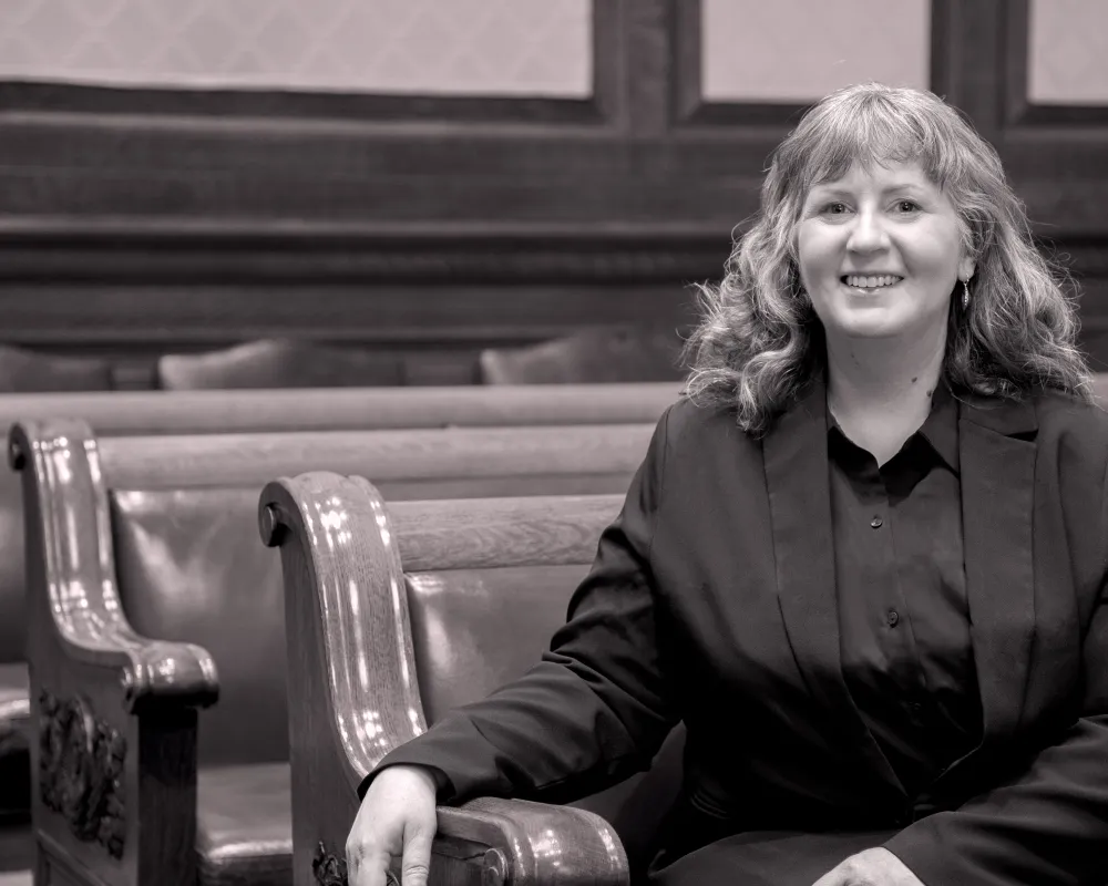 Laura Edmonston sits on the end of a bench row in a court room.