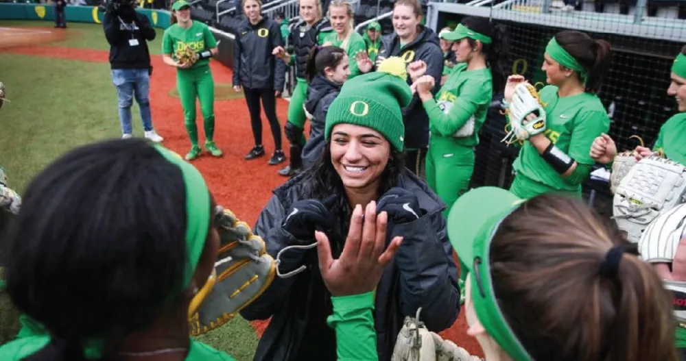 A University of Oregon softball player high-fiving her teammates. 