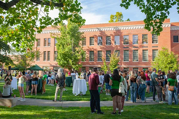 A crowd of people mill around the quad outside Chapman Hall in the background.