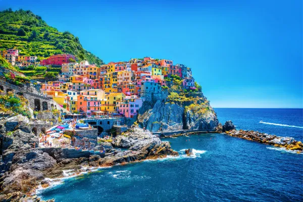 Multicolored buildings cover a cliff edge above the blue waters of the Amalfi Coast.