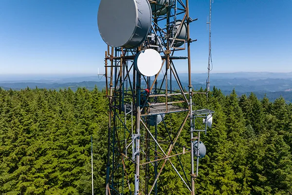 A metal structure with dishes and sensors rises above evergreen trees in the Oregon mountains.