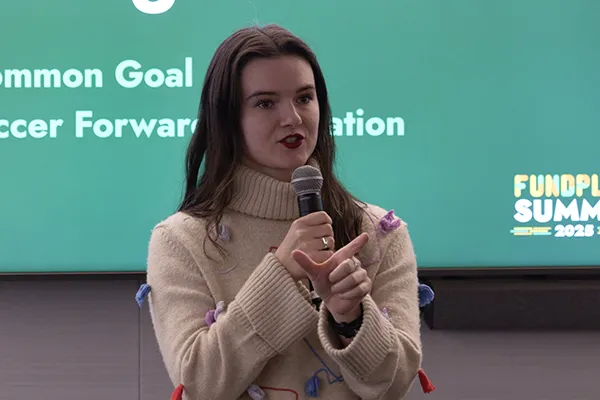 Bailey Holloway, a white woman with long brown hair, speaks into a microphone.