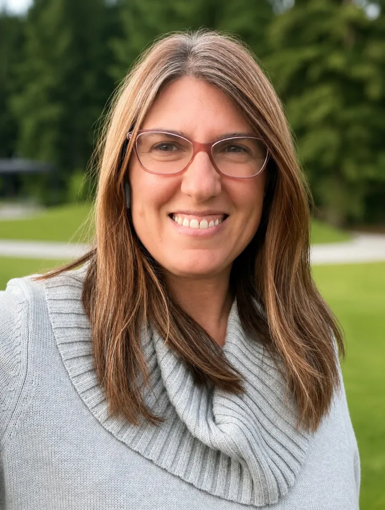 A headshot of a white woman in glasses and a gray sweater.