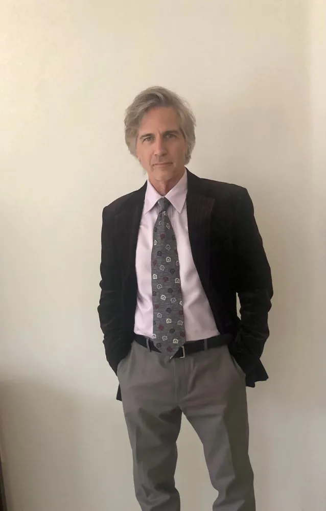 A man with gray hair wearing a suit jacket and tie.