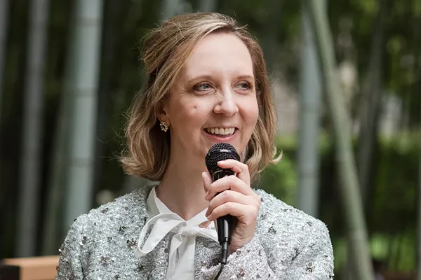 A white woman smiles holding a microphone.