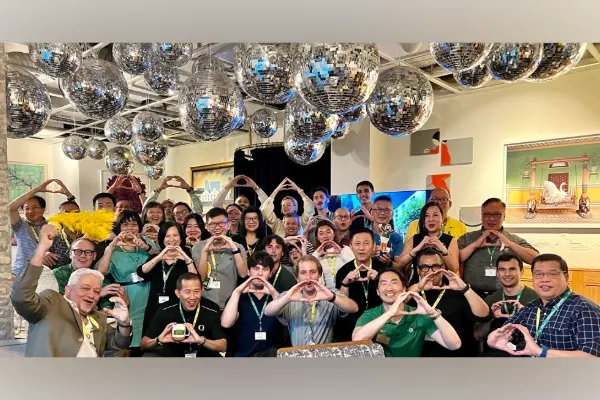 A group of people in Singapore standing under many hanging disco balls each make the shape of an O with their hands.