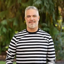 A white male wearing a striped white and black long sleeve shirt.