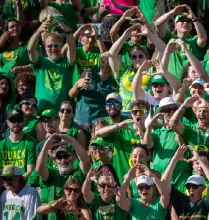 Ducks fans in a stadium forming an "O" with their hands.