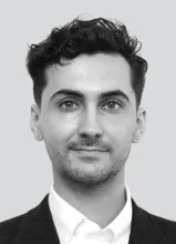 A black and white headshot of David Purucker, a white man in a suit with coiffed hair.