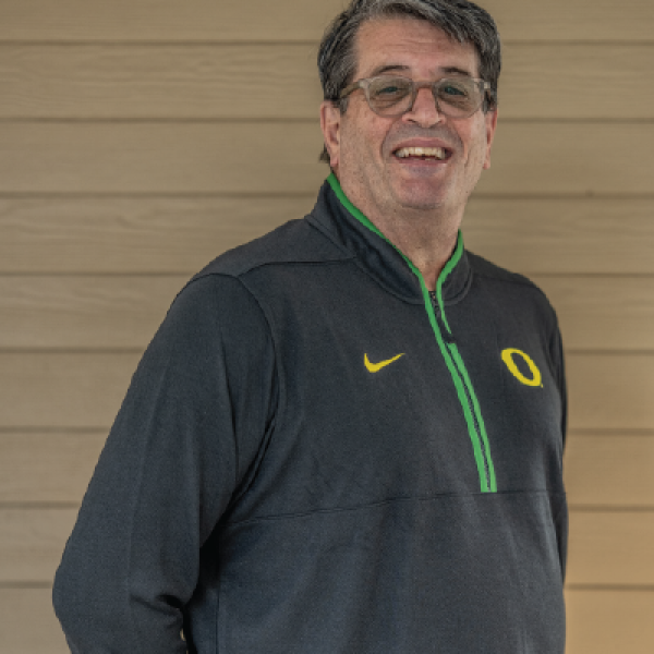 Fred Poust smiles at the camera in a dark gray Oregon pullover.