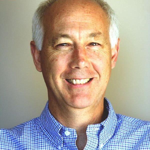 Headshot of Kevin Johnston, a white man with white hair wearing a blue button up shirt and 