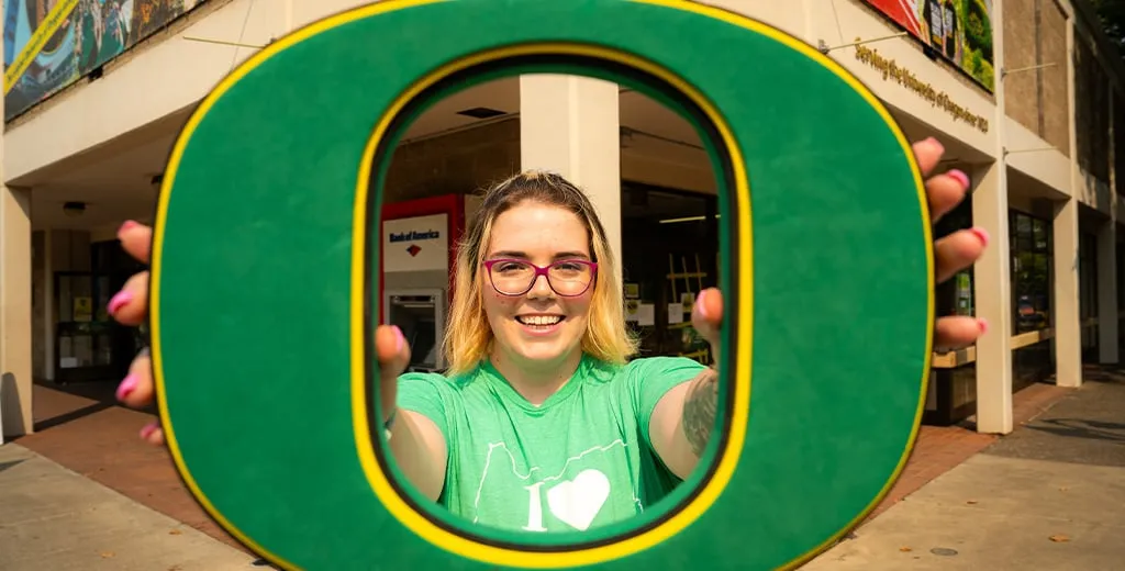 Young Woman holding up University of Oregon O logo