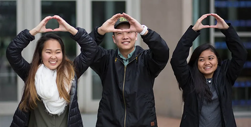 Three University of Oregon students holding up O logo