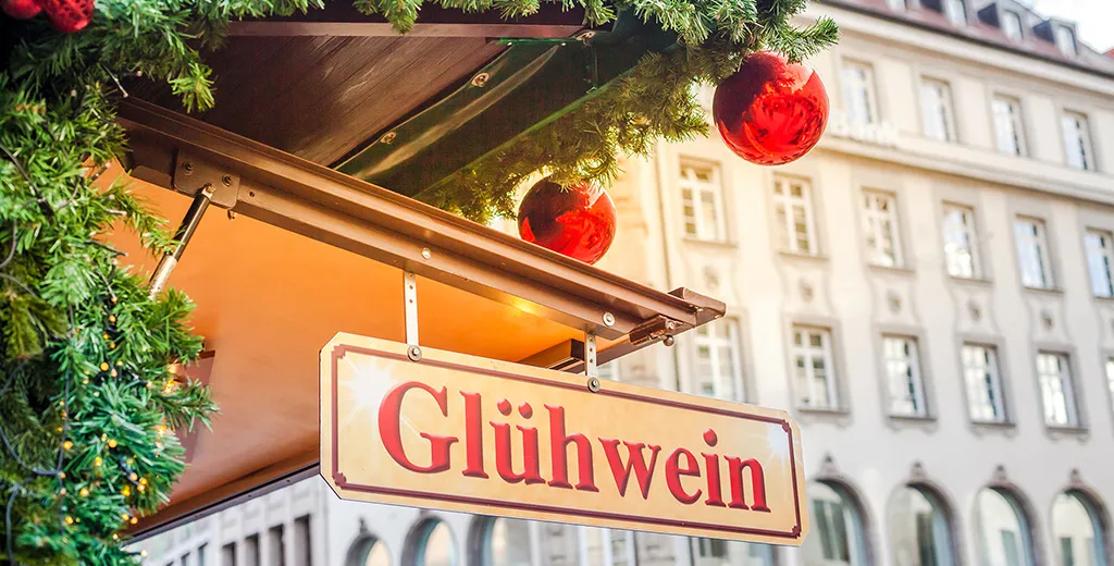 A hanging sign for gluhwein outside a festively decorated shop