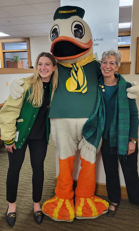 Two people posing for a picture with the UO Duck mascot. 