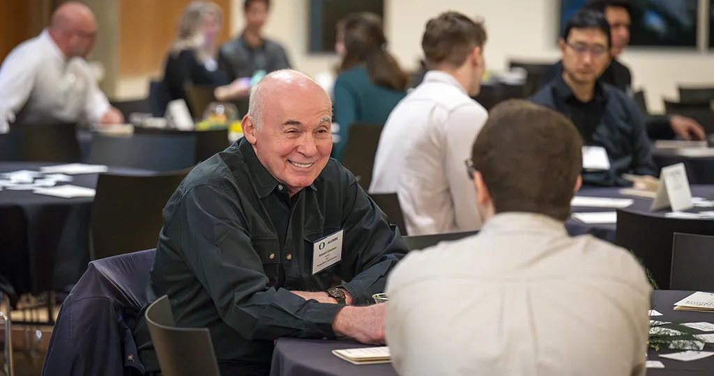 Alumni man have a conversation with a student.