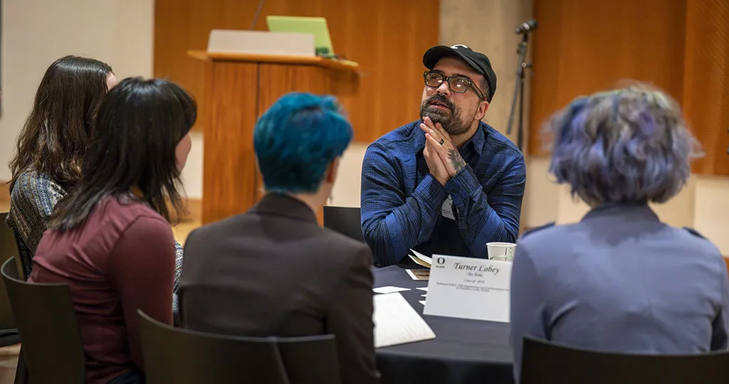 An Alumni man having a conversation with multiple students. 