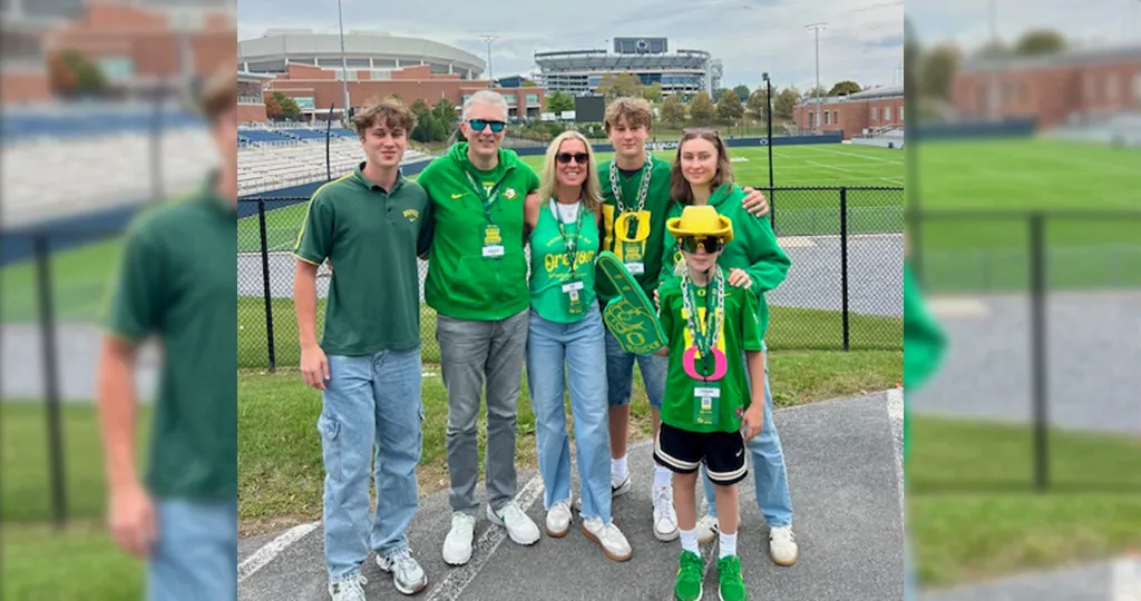 The East family poses in front of Beaver Stadium wearing green Oregon gear.