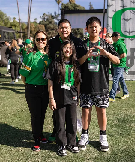 A group of University of Oregon Ducks fans posing wearing Ducks gear and event lanyards. 