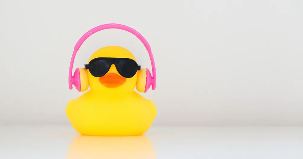 A yellow robber duck wears pink headphones and black sunglasses.