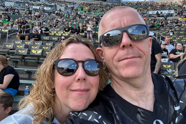James and Emma Hathway wear sunglasses in a selfie with the stands of Autzen Stadium behind them.