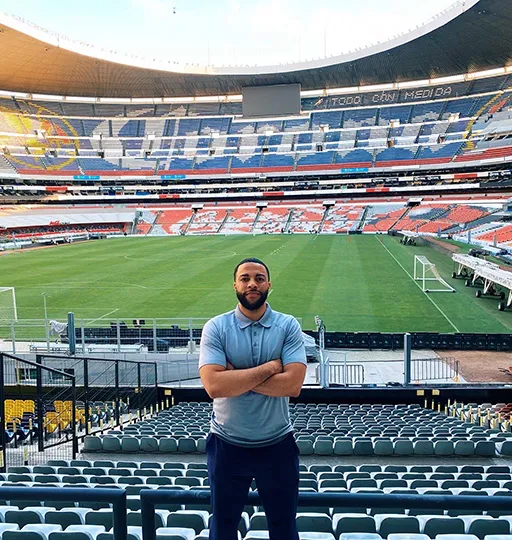 A person standing in the stands at a soccer field. 