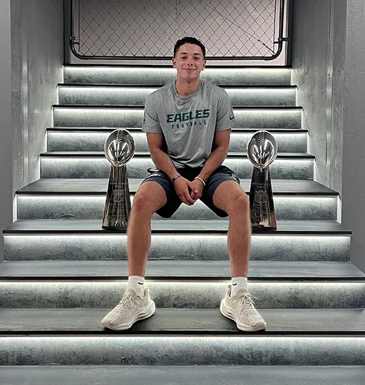 A person sitting on steps with a trophy on both sides. 