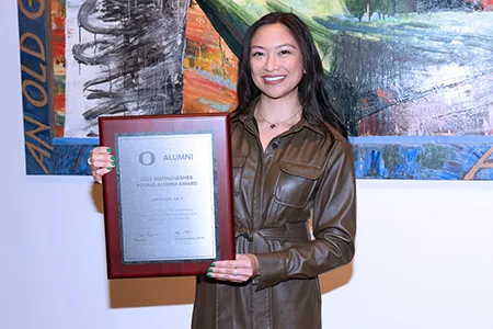 Lorie Acio holds her Distinguished Young Alumni Award plaque.