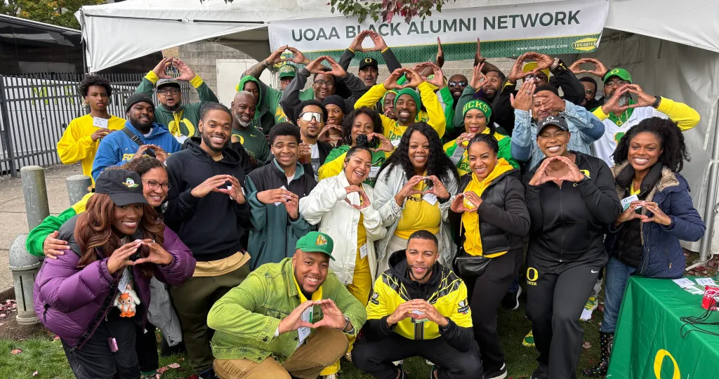 A large group of UOBAN members pose for a photo at a football tailgate.