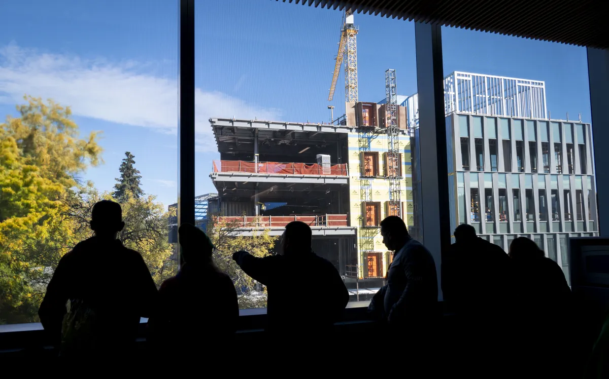 Alumni look out the window of a campus building toward the construction of the Knight Campus.