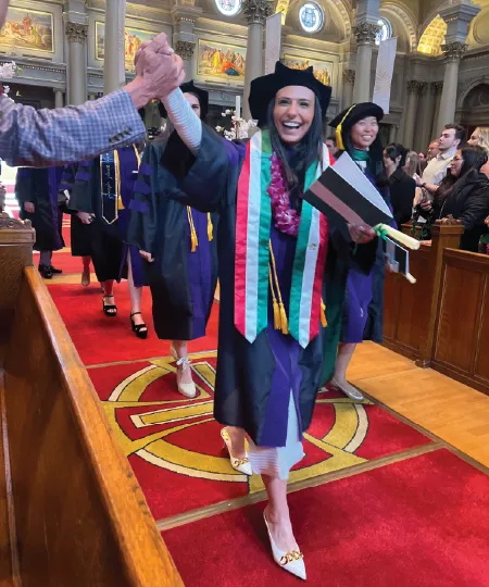 A law student walking down an aisle in joy after graduating. 