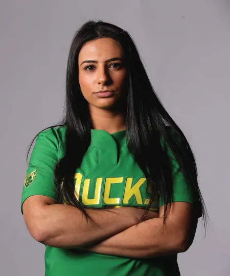 A University of Oregon softball player posing with her arms crossed and a serious facial expression. 