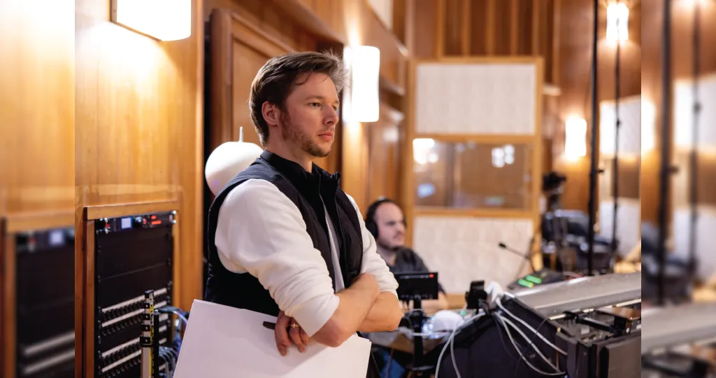 A music conductor standing with their arms crossed. 